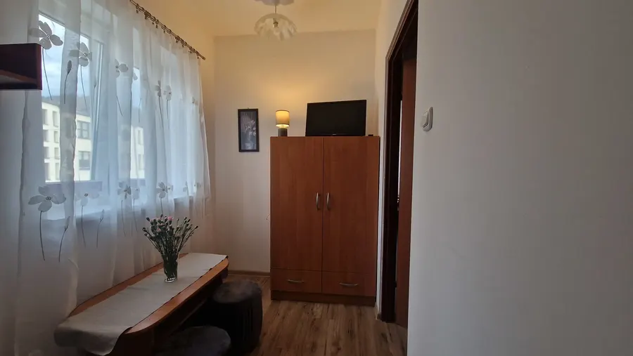 Pokój z szafą, telewizorem i ławą przy oknie