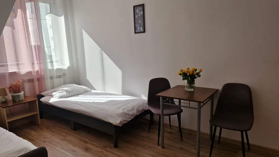 Jasny pokój z łóżkiem, stolikiem i dwoma krzesłami