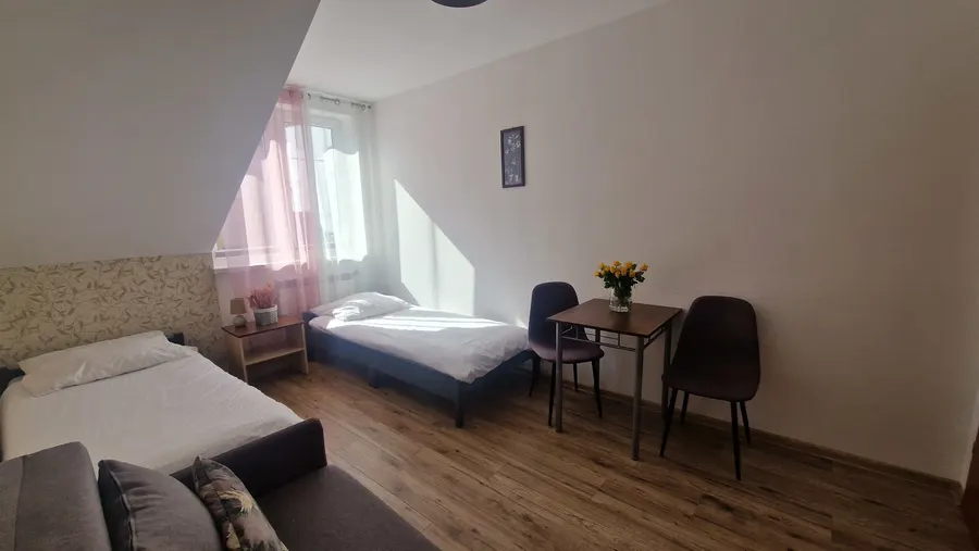 Pokój z sofą, dwoma łóżkami i stolikiem przy oknie