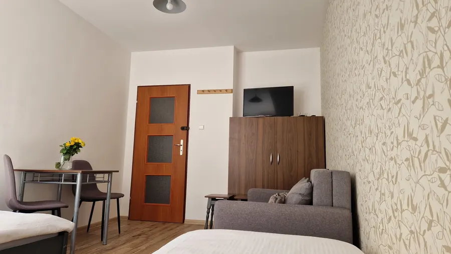 Pokój trzyosobowy z szafą, telewizorem i sofą
