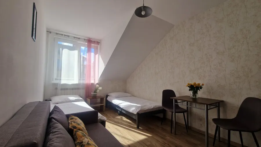 Pokój pod skosem z sofą, łóżkiem i stolikiem